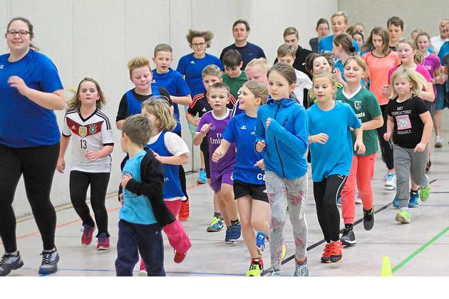 Aufwärmen in der Halle: Etwa 25 bis 30 Kinder und Jugendliche, angefangen von den Jüngsten im Grundschulalter bis zu den Älteren im Alter von etwa 18 oder 19 Jahren, traben zunächst gemeinsam durch die Halle.